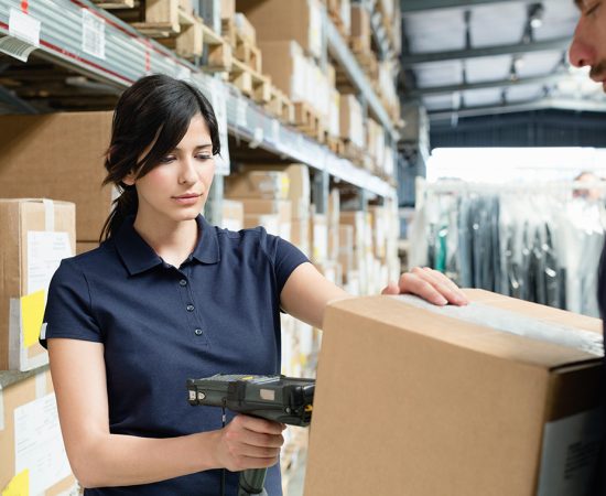 Warehouse workers using barcode scanner on box in distribution warehouse Warehouse workers using barcode scanner on box in distribution warehouse